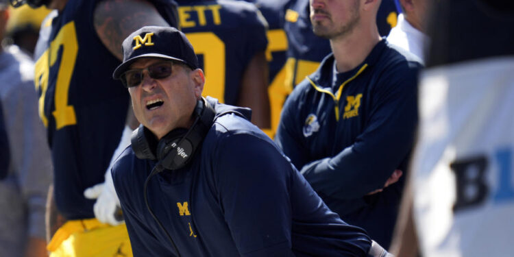 FILE - Michigan head coach Jim Harbaugh, front left, watches against Rutgers as analytics assistant Connor Stalions, right, looks on during an NCAA college football game in Ann Arbor, Mich., Sept. 23, 2023. A Michigan judge who champions peacemaking principles in court will preside over a hearing on Friday that will determine whether Jim Harbaugh can coach and close the regular season on the field with the third-ranked Wolverines. Attorneys for Harbaugh and the university are asking Judge Timothy P. Connors to at least temporarily lift the Big Ten’s penalty against him for a sign-stealing scheme. (AP Photo/Paul Sancya, FILE)