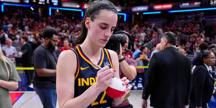 Caitlin Clark signs a ball