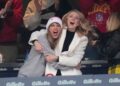 Taylor Swift in a grey sweatshirt excitedly hugs Brittany Mahomes in a white jacket