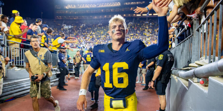 ANN ARBOR, MICHIGAN - AUGUST 31: Davis Warren #16 of the Michigan Wolverines interacts with fans as he walks off the field after a college football game against the Fresno St. Bulldogs at Michigan Stadium on August 31, 2024 in Ann Arbor, Michigan. The Michigan Wolverines won the game 30-10. (Photo by Aaron J. Thornton/Getty Images)