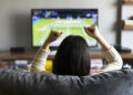 young woman watching Tennis on television and cheering