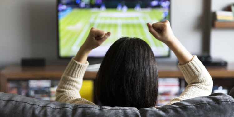 young woman watching Tennis on television and cheering