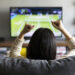 young woman watching Tennis on television and cheering