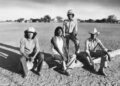 Etchohuaquila, Sonora, Mexico - VALENZUELA FAMILY - Left to right, Daniel, Avelino, Francisco and Manuel Valenzuela, visit the field where they all learned to play baseball, April 27, 1981. The small town of Etchohuaquila, in the municipality of Navojoa in the state of Sonora, Mexico, is seen in the background, as the brothers sit on the log that serves as the team bench. Photo Credit: Jose Galvez / Los Angeles Times