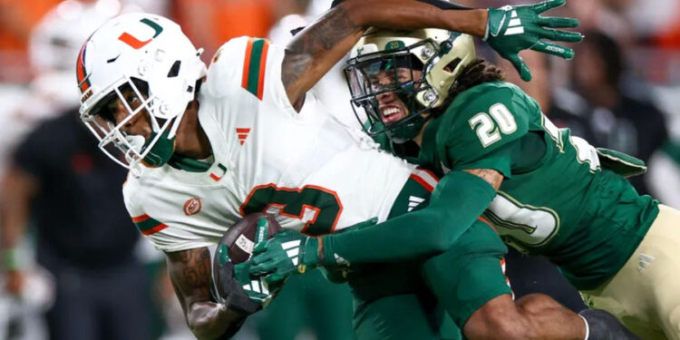 Sep 21, 2024; Tampa, Florida, USA; Miami Hurricanes wide receiver Jacolby George (3) is tackled by South Florida Bulls cornerback Brent Austin (20) in the first quarter at Raymond James Stadium. Mandatory Credit: Nathan Ray Seebeck-Imagn Images