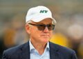 Woody Johnson looks on field