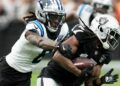 Las Vegas Raiders wide receiver Davante Adams is tackled by Carolina Panthers cornerback Jaycee Horn.