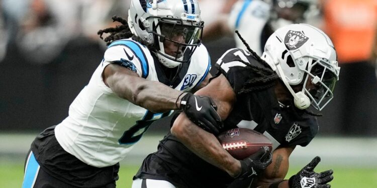 Las Vegas Raiders wide receiver Davante Adams is tackled by Carolina Panthers cornerback Jaycee Horn.