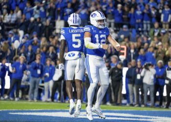 BYU wide receiver Darius Lassiter (5) and quarterback Jake Retzlaff (12) celebrate after Retzlaff ran for a touchdown in the first half of an NCAA college football game against Oklahoma State, Friday, Oct. 18, 2024, in Provo, Utah. (AP Photo/Spenser Heaps)