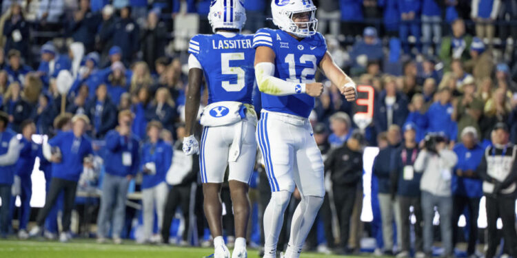 BYU wide receiver Darius Lassiter (5) and quarterback Jake Retzlaff (12) celebrate after Retzlaff ran for a touchdown in the first half of an NCAA college football game against Oklahoma State, Friday, Oct. 18, 2024, in Provo, Utah. (AP Photo/Spenser Heaps)