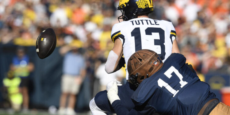 CHAMPAIGN, IL - OCTOBER 19: Michigan Wolverines Quarterback Jack Tuttle (13) fumbles the ball during the college football game between the Michigan Wolverines and the Illinois Fighting Illini on October 19, 2024, at Memorial Stadium, in Champaign, Illinois. (Photo by Michael Allio/Icon Sportswire via Getty Images)