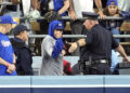 A law enforcement officer talks with a fan who reached over the outfield wall to catch a fly ball by New York Yankees' Gleyber Torres during the ninth inning in Game 1 of the baseball World Series, Friday, Oct. 25, 2024, in Los Angeles. (AP Photo/Godofredo A. Vásquez)