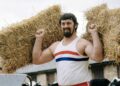 Geoff Capes holds straw bales