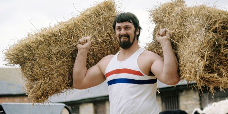 Geoff Capes holds straw bales