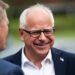 Tim Walz, man with white hair, smiling with black rimmed glasses