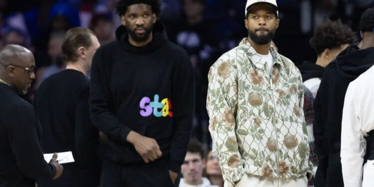 Nov 2, 2024; Philadelphia, Pennsylvania, USA; Injured Philadelphia 76ers Paul George (R) and Joel Embiid (L) look on during the first quarter against the Memphis Grizzlies at Wells Fargo Center. Mandatory Credit: Bill Streicher-Imagn Images