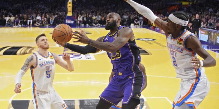 Los Angeles Lakers forward LeBron James, center, shoots as Oklahoma City Thunder center Isaiah Hartenstein, left, and guard Shai Gilgeous-Alexander defend during the first half of an Emirates NBA Cup basketball game, Friday, Nov. 29, 2024, in Los Angeles. (AP Photo/Mark J. Terrill)