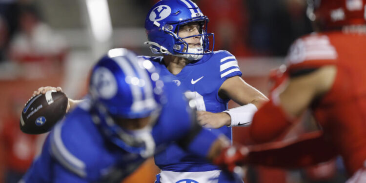 SALT LAKE CITY, UT - NOVEMBER 9:  Jake Retzlaff #12 of the Brigham Young Cougars throws a pass under pressure from the Utah Utes during the first half of their game at Rice-Eccles Stadium on November 9, 2024 in Salt Lake City, Utah.(Photo by Chris Gardner/Getty Images)