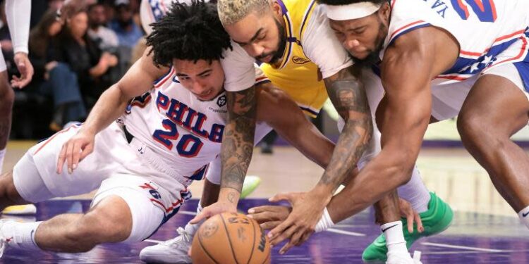 Lakers guard D'Angelo Russell battles 76ers Jared McCain and Guerschon Yabusele for a loose ball at Crypto.com Arena.