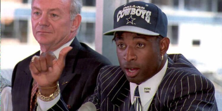 Deion Sanders talks to reporters at a press conference in Irving, Texas after the Dallas Cowboys signed him for "significant dollars." Cowboys owner Jerry Jones (L), who declined to release details of the contract said "Its a done deal."