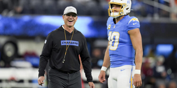 Los Angeles Chargers head coach Jim Harbaugh smiles next to quarterback Justin Herbert (10) before an NFL football game against the Cincinnati Bengals, Sunday, Nov. 17, 2024, in Inglewood, Calif. (AP Photo/Gregory Bull)