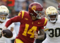 LOS ANGELES, CALIFORNIA - NOVEMBER 30: Quarterback Jayden Maiava #14 of the USC Trojans is chased out of the pocket by safety Xavier Watts #0 and defensive lineman Bryce Young #30 of the Notre Dame Fighting Irish during the first half at United Airlines Field at the Los Angeles Memorial Coliseum on November 30, 2024 in Los Angeles, California. (Photo by Kevork Djansezian/Getty Images)