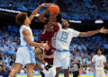 CHAPEL HILL, NORTH CAROLINA - NOVEMBER 04:  TK Simpkins #3 of the Elon Phoenix drives to the basket between Seth Trimble #7 and Jalen Washington #13 of the North Carolina Tar Heels during the first half of the game at the Dean E. Smith Center on November 04, 2024 in Chapel Hill, North Carolina.  (Photo by Grant Halverson/Getty Images)