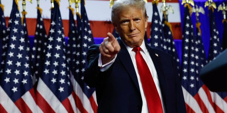 Donald Trump standing in front of American flags