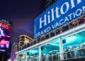 A large Hilton Grand Vacations sign with people looking out over a deck.