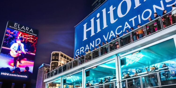 A large Hilton Grand Vacations sign with people looking out over a deck.