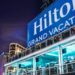 A large Hilton Grand Vacations sign with people looking out over a deck.