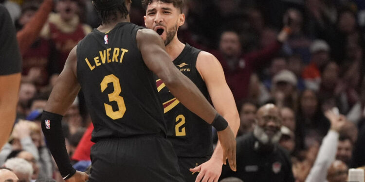 Cleveland Cavaliers guard Ty Jerome, right, celebrates a three-point basket with teammate Caris LeVert (3) in the first half of an NBA basketball game against the Golden State Warriors, Friday, Nov. 8, 2024, in Cleveland. (AP Photo/Sue Ogrocki)