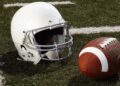 Football and football helmet on gridiron