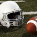 Football and football helmet on gridiron