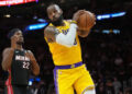 Dec 4, 2024; Miami, Florida, USA; Los Angeles Lakers forward LeBron James (23) grabs a rebound in front of Miami Heat forward Jimmy Butler (22) in the first half at Kaseya Center. Mandatory Credit: Jim Rassol-Imagn Images