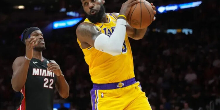 Dec 4, 2024; Miami, Florida, USA; Los Angeles Lakers forward LeBron James (23) grabs a rebound in front of Miami Heat forward Jimmy Butler (22) in the first half at Kaseya Center. Mandatory Credit: Jim Rassol-Imagn Images