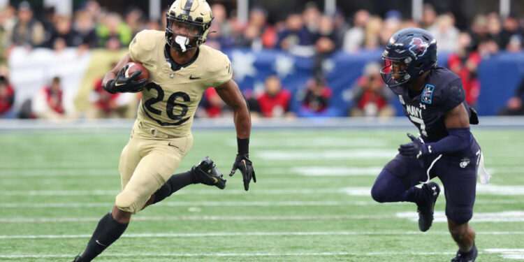 FOXBOROUGH, MA - DECEMBER 09: Army Black Knights running back Kanye Udoh (26) pursued by Navy Midshipmen defensive end Mbiti Williams Jr. (7) during the 124th Army-Navy football game on December 9, 2023, at Gillette Stadium in Foxborough, MA. (Photo by M. Anthony Nesmith/Icon Sportswire via Getty Images)