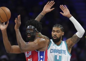 Philadelphia 76ers' Joel Embiid, left, tries to pass against Charlotte Hornets' Nick Richards during the first half of an NBA basketball game, Friday, Dec. 20, 2024, in Philadelphia. (AP Photo/Matt Slocum)