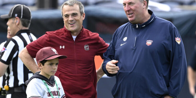 Illinois head coach Bret Bielema, right, and South Carolina head coach Shane Beamer chat on the field before the Citrus Bowl NCAA college football game, Tuesday, Dec. 31, 2024, in Orlando, Fla. (AP Photo/Phelan M. Ebenhack)