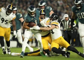 Philadelphia Eagles quarterback Jalen Hurts (1) is tackled by Pittsburgh Steelers linebacker Alex Highsmith (56) and Pittsburgh Steelers linebacker T.J. Watt, right, during the first half of an NFL football game Sunday, Dec. 15, 2024, in Philadelphia. (AP Photo/Matt Slocum)