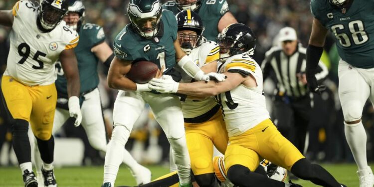 Philadelphia Eagles quarterback Jalen Hurts (1) is tackled by Pittsburgh Steelers linebacker Alex Highsmith (56) and Pittsburgh Steelers linebacker T.J. Watt, right, during the first half of an NFL football game Sunday, Dec. 15, 2024, in Philadelphia. (AP Photo/Matt Slocum)