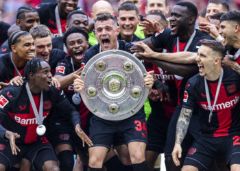 LEVERKUSEN, GERMANY - MAY 18: Granit Xhaka of Leverkusen celebrates the winning of championship trophy with Jeremie Frimpong of Leverkusen (L), Florian Wirtz of Leverkusen (3.L), Victor Boniface of Leverkusen (3.L) and Alejandro Grimaldo of Leverkusen at the winning ceremony after the Bundesliga match between Bayer 04 Leverkusen and FC Augsburg at BayArena on May 18, 2024 in Leverkusen, Germany.(Photo by Mika Volkmann/Getty Images)