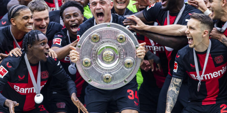 LEVERKUSEN, GERMANY - MAY 18: Granit Xhaka of Leverkusen celebrates the winning of championship trophy with Jeremie Frimpong of Leverkusen (L), Florian Wirtz of Leverkusen (3.L), Victor Boniface of Leverkusen (3.L) and Alejandro Grimaldo of Leverkusen at the winning ceremony after the Bundesliga match between Bayer 04 Leverkusen and FC Augsburg at BayArena on May 18, 2024 in Leverkusen, Germany.(Photo by Mika Volkmann/Getty Images)