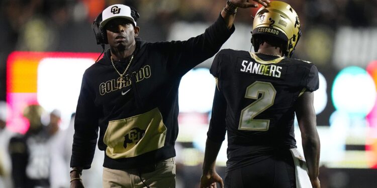 Deion Sanders pats Shedeur Sanders on helmet