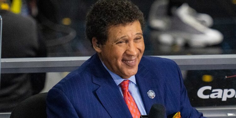 Greg Gumbel looks on