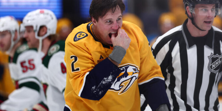 NASHVILLE, TENNESSEE - JANUARY 18:  Luke Schenn #2 of the Nashville Predators checks his teeth after a fight against Marcus Foligno #17 of the Minnesota Wild in the first period on January 18, 2025 at Bridgestone Arena in Nashville. (Photo by Casey Gower/NHLI via Getty Images)