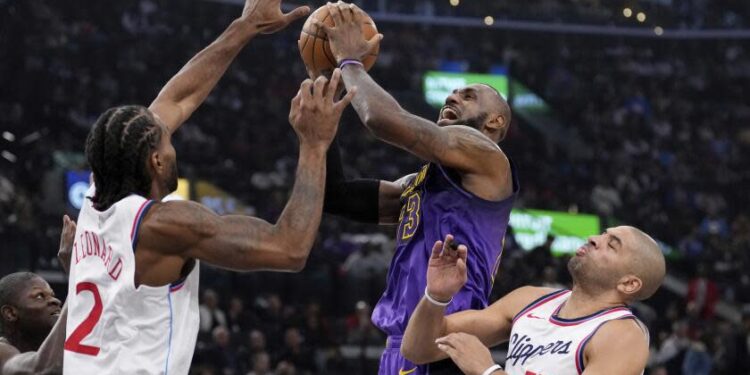 Los Angeles Lakers forward LeBron James, center, shoots as Los Angeles Clippers forward Kawhi Leonard.