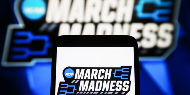 UKRAINE - 2024/04/09: In this photo illustration, a March Madness (NCAA Division I men's basketball tournament) logo is seen on a smartphone and a pc screen. (Photo Illustration by Pavlo Gonchar/SOPA Images/LightRocket via Getty Images)