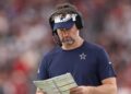 Brian Schottenheimer looks at a play sheet during a Cowboys game