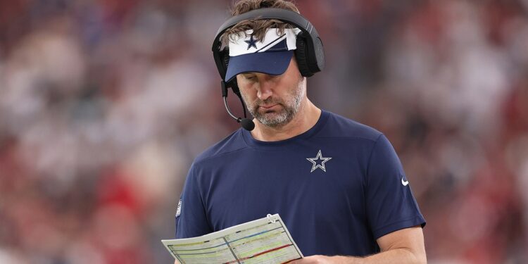 Brian Schottenheimer looks at a play sheet during a Cowboys game